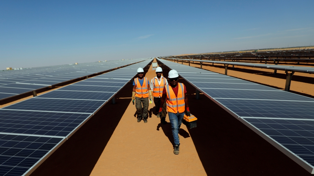 Workers walk between photovoltaic panels at the Benban plant in Aswan