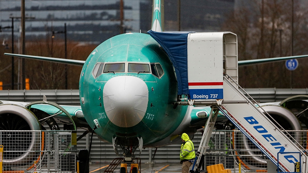 An employee walks past a Boeing 737 Max aircraft seen parked at the Renton Municipal Airport in Renton, Washington, U.S. January 10, 2020