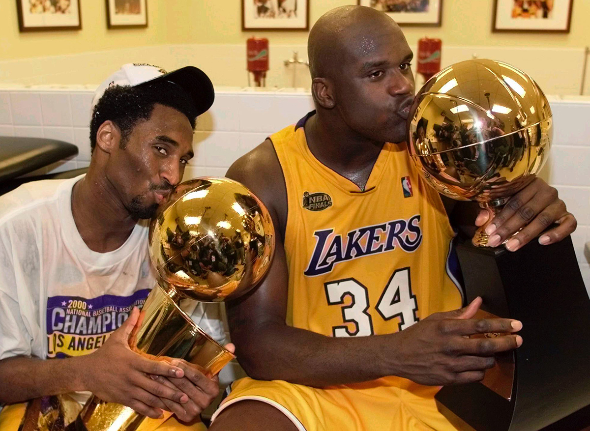 Los Angeles Lakers center Shaquille O''Neal (R) kisses the Most Valuable Player trophy as teammate Kobe Bryant kisses the NBA championship trophy as they celebrate in the locker room after winning the