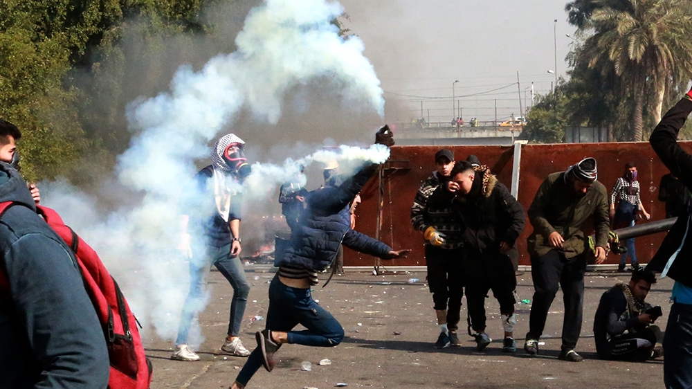 An Iraqi protester runs to throw tear gas canister back towards riot police forces during clashes with anti-riot police forces in central Baghdad, Iraq, 20 January 2020. According to media reports, tw