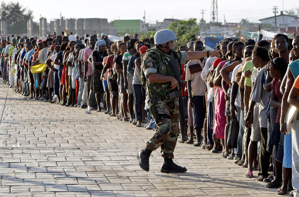 A U.N. soldier patrols where earthquake survivors line up for food distributed by the UN near Cite Soleil in Port-au-Prince, Haiti, Saturday, Jan. 16, 2010. A 7.0-magnitude earthquake hit Haiti on Tu