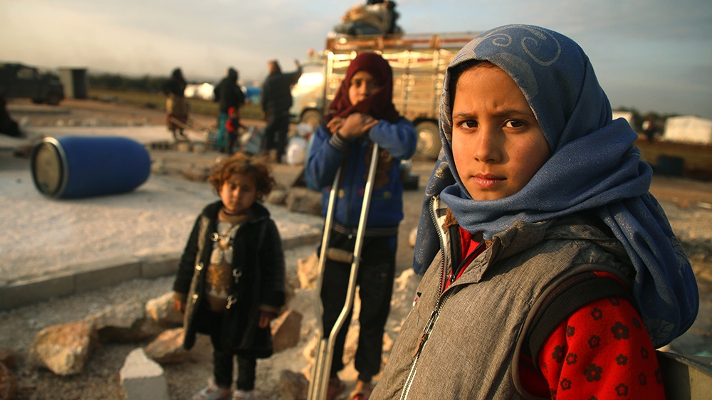 Syrian children pose for a picture as their families prepare to flee a camp for the displaced, east of Sarmada in the north of the northwestern Idlib province, on February 16, 2020, amid an ongoing pr