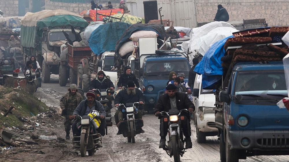 Men riding on motorbikes pass the trucks that carry belongings of displaced Syrians, in northern Idlib, Syria January 30, 2020. Picture taken January 30, 2020. REUTERS/Khalil Ashawi