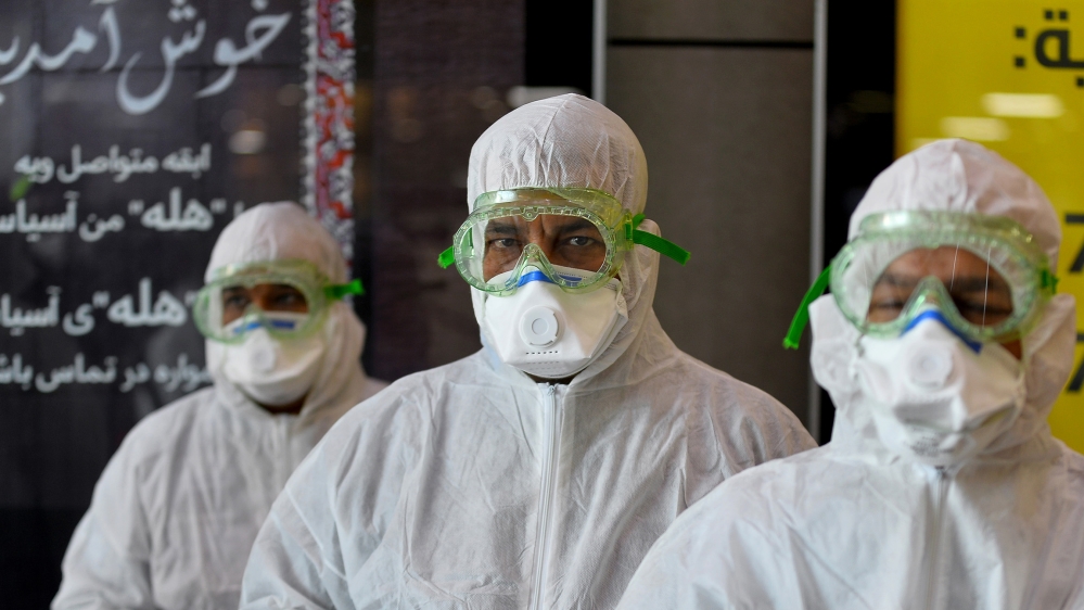 A medical team wearing protective outfit awaits to check Iraqi passengers returning from Iran upon their arrival at the Najaf International Airport on February 21, 2020, after Iran announced cases of