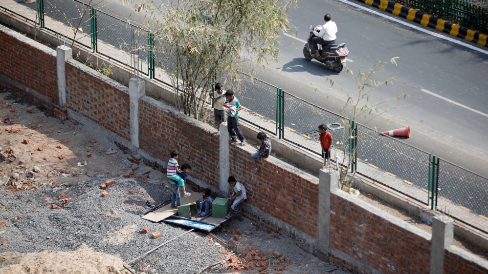 Children play on a wall that was built along a slum area as part of a beautification drive along a route that US President Trump and India''s PM Modi will be taking during Trump''s visit later this mont
