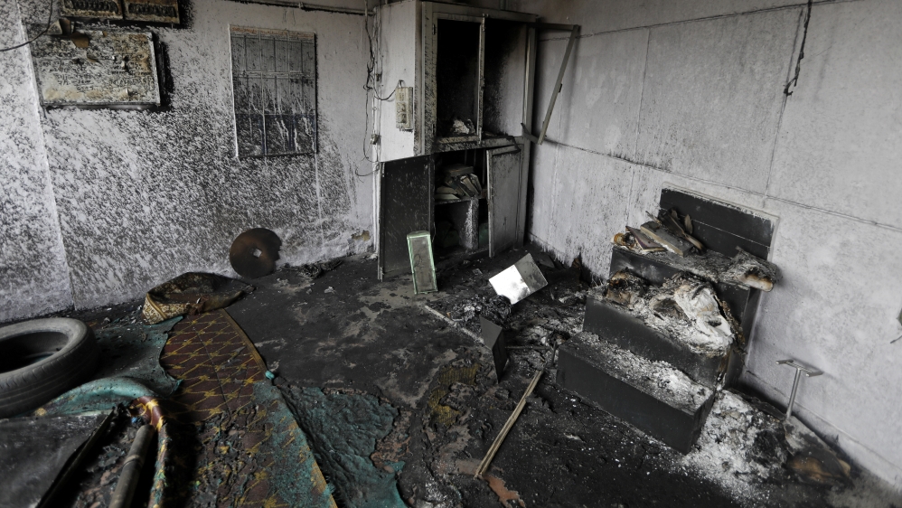 Firefighters douse the burning wreckage of a shop at a tyre market after it was set on fire by a mob in a riot affected area after clashes erupted between people demonstrating for and against a new ci