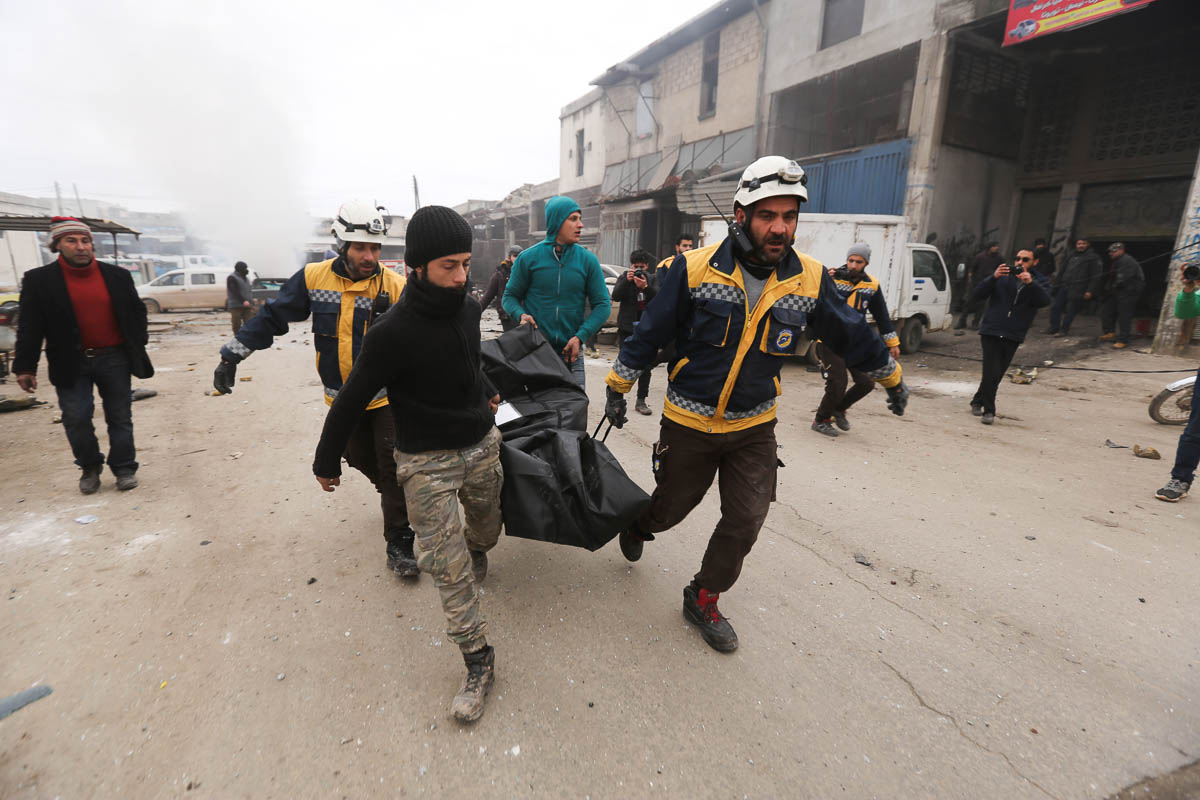 Emergency services carry a body of a person killed in a government airstrike in the city of Idlib, Syria, Tuesday, Feb. 11, 2020. The latest violence in Idlib came as government forces came closer to