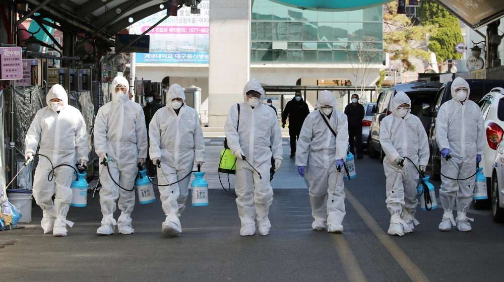 Market workers wearing protective gear spray disinfectant at a market in the southeastern city of Daegu on February 23, 2020 as a preventive measure after the COVID-19 coronavirus outbreak. South Kore