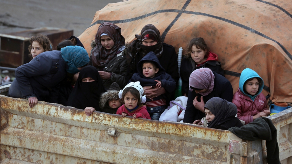 Syrians sit in the back of a truck as they flee the advance of the government forces in the province of Idlib, Syria, towards the Turkish border, Thursday, Jan. 30, 2020. Warplanes struck a town in a