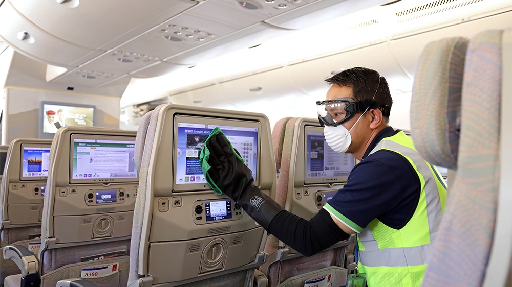 A handout image provided by Emirates airlines on March 8, 2020 in Dubai shows a member of the cleaning staff disinfecting seat screens aboard an Emirates Airbus A380-800 aircraft for sterilisation eff
