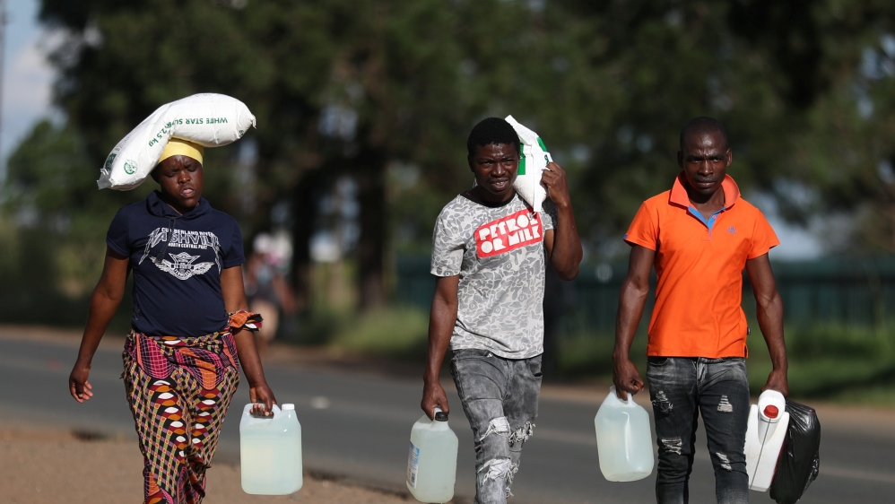 People carry bags of maize and paraffin as they return from a store ahead of a nationwide lockdown, in Johannesburg