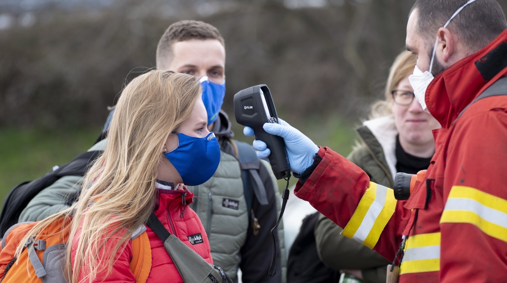 A Slovak firefighter checks the temperature of a woman wearing a protective facemask due to the coronavirus COVID-19 crossing the Bratislava-Jarovce border crossing between Austria and Slovakia on Mar