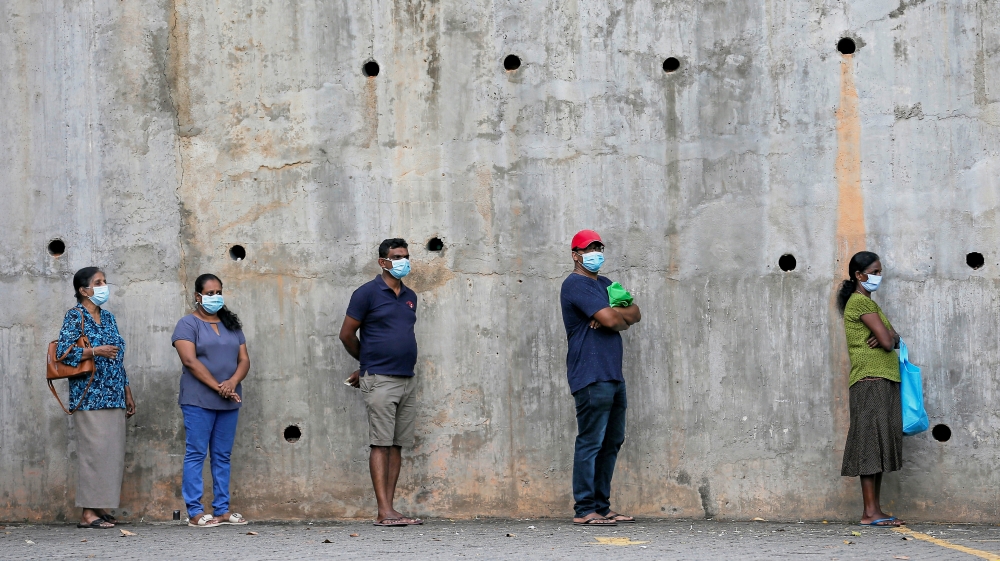 People maintain the one-meter distance in-between each other as they stand in a line to buy groceries at a supermarket during the time government lifted the curfew in Colombo
