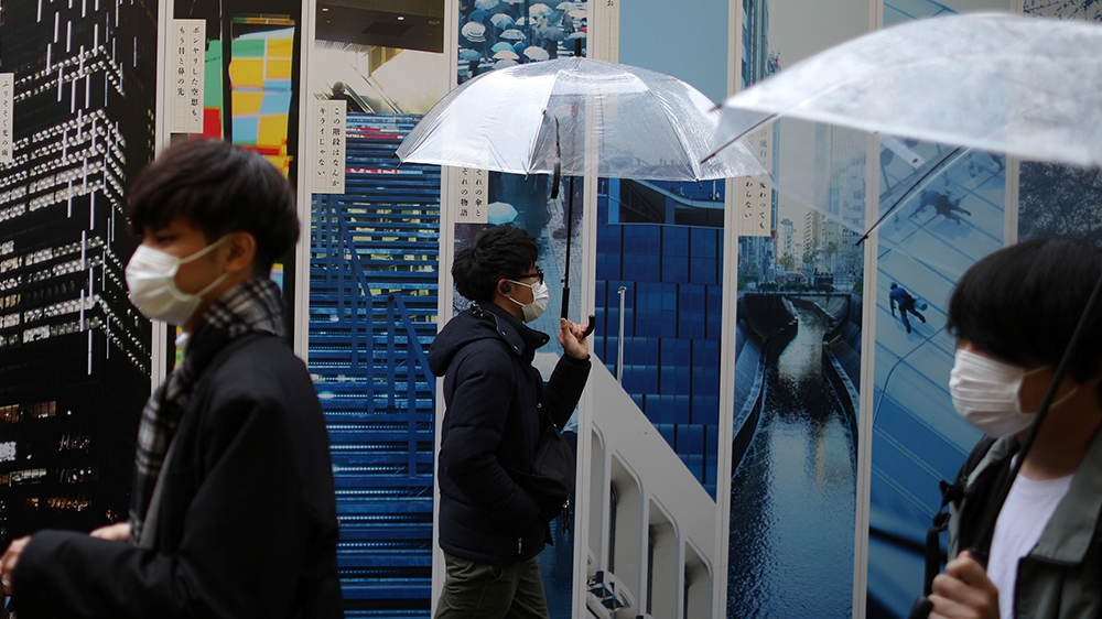 People, wearing protective face masks, following an outbreak of the coronavirus disease (COVID-19), walk on a street near Shibuya station in Tokyo, Japan March 8, 2020. REUTERS/Stoyan Nenov
