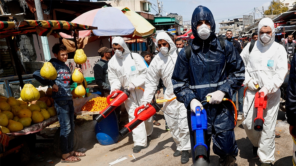 Workers wearing protective gear spray disinfectant as a precaution against the coronavirus, at the main market in Gaza City, Thursday, March 19, 2020. The Middle East has some 20,000 cases of the viru