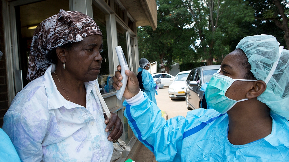 A woman is screened by a Health worker before visiting a relative at a public hospital in Harare, Zimbabwe ,Saturday, March, 21, 2020 . Zimbabwe announced its first case of coronavirus,in one of 