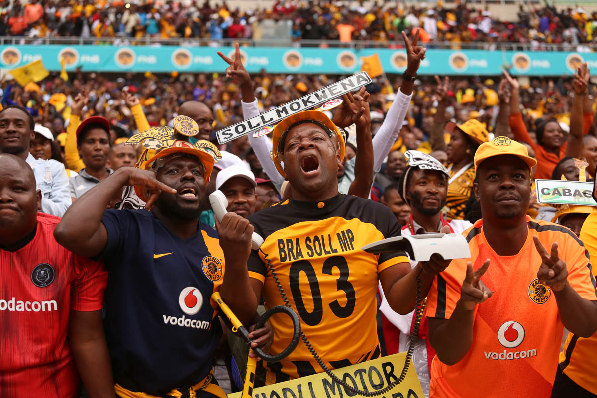 Kaizer chiefs fans react to missed chance of scoring by one of the clubs strikers. He also has cordless phone gadget as his colleague on his right gestures as if to call the coach to make changes.Phot
