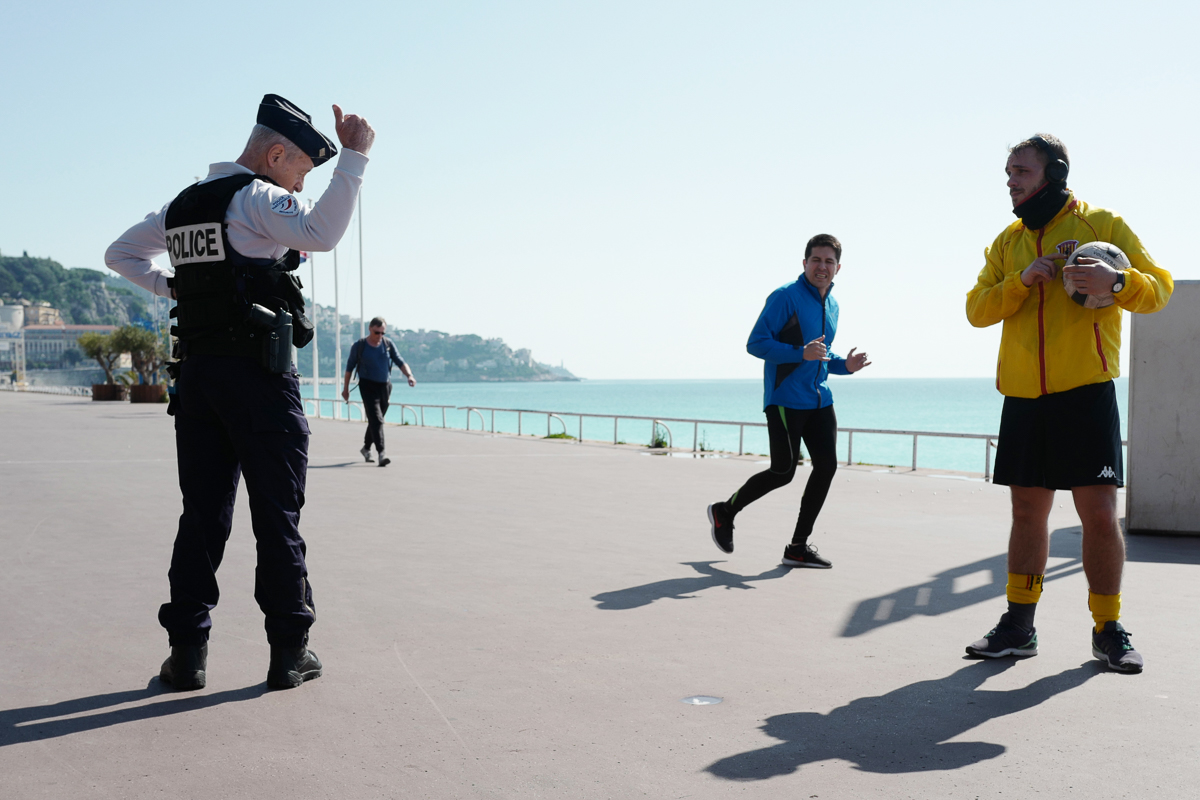 A French Police Nationale officer gestures and talks to a man on the "Promenade des Anglais" in the French Riviera city of Nice, on March 18, 2020, a day after a strict lockdown came into effect in Fr