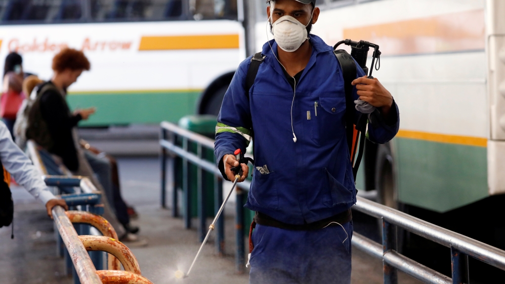 A health worker sprays disinfectant on railings to combat the spread of coronavirus disease (COVID-19) at a bus depot in Cape Town