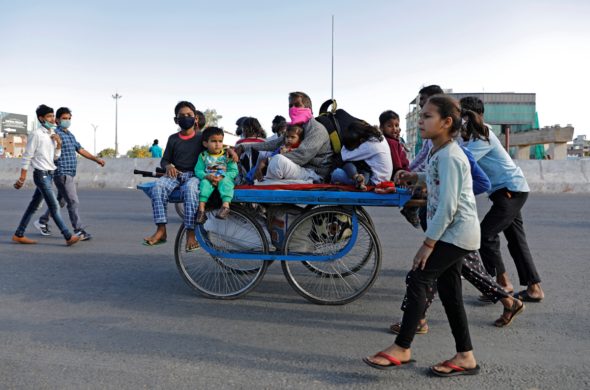 A migrant worker rides a cart with his family on a highway as they return to their villages, during a 21-day nationwide lockdown to limit the spreading of coronavirus disease (COVID-19), in Ghaziabad,