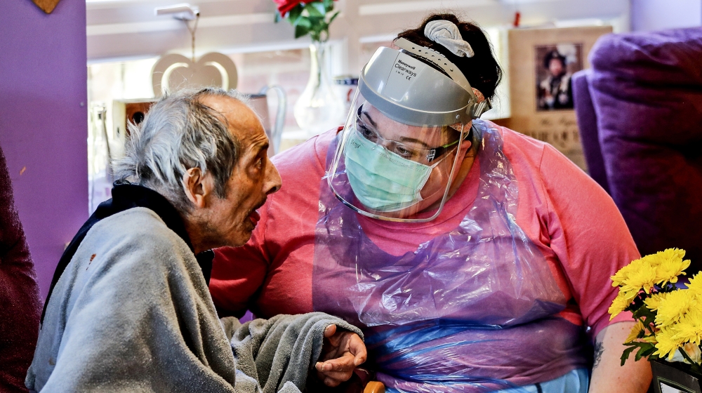 A nurse in PPE speaks to a resident at the Wren Hall care home in Nottingham, Monday, April 20, 2020. AP visited a care home in Nottingham where 10 of their 54 residents have succumbed to coronavirus.