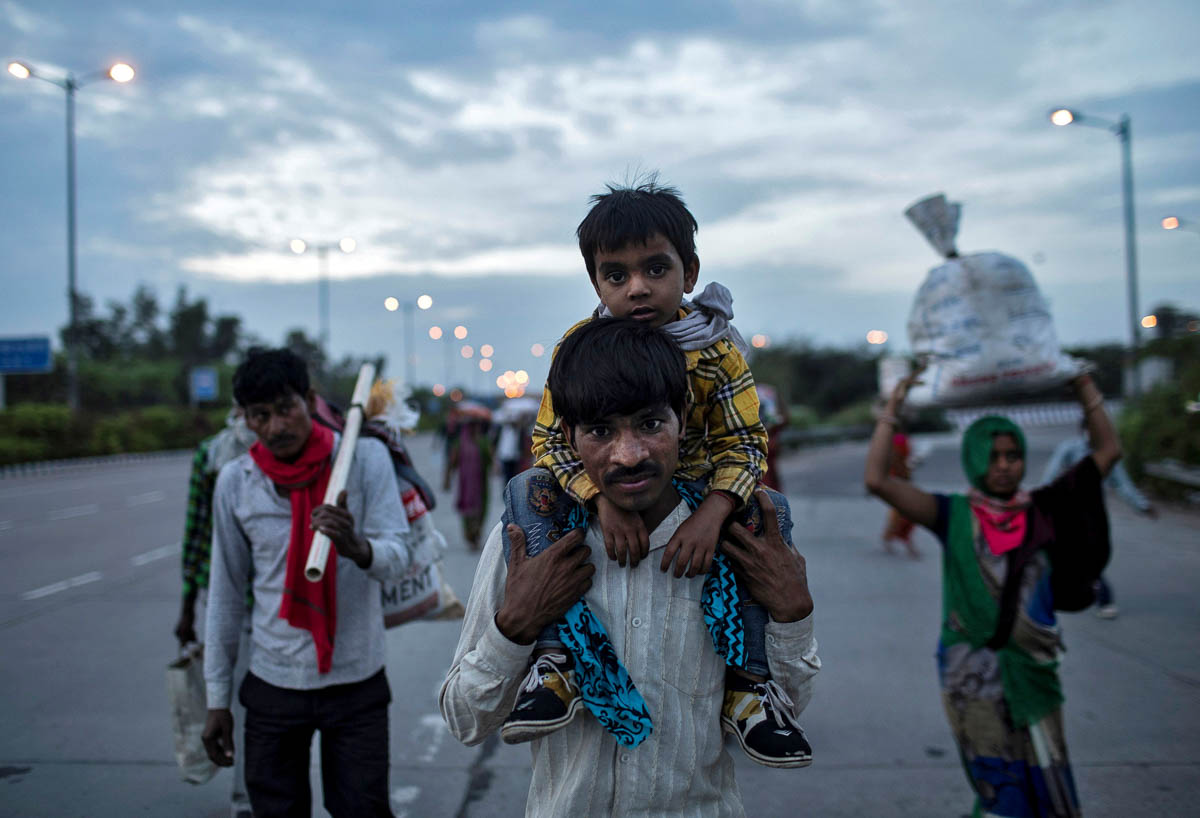 Dayaram Kushwaha, a migrant worker, carries his 5-year-old son, Shivam, on his shoulders as they walk along a road to return to their village, during a 21-day nationwide lockdown to limit the spreadin