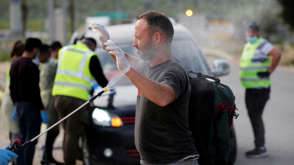 A Palestinian worker is sprayed with disinfectants as a precaution against the spread of the coronavirus disease (COVID-19), upon his return from Israel, outside the Israeli-controlled Tarqumiya check