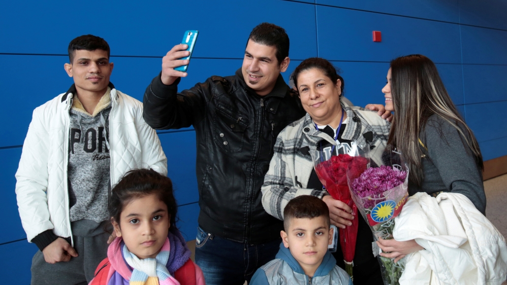 Iraqi refugee Amira Al-Qassab and four of her children are reunited with her son Rami as he uses his phone to Facetime the event to a relative as they arrive at Detroit Metro Airport