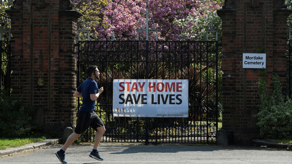 A man jogs past a public health message attached to gates of a cemetery in London as the spread of the coronavirus disease (COVID-19) continues, London, Britain, April 11, 2020. REUTERS/Toby Melville