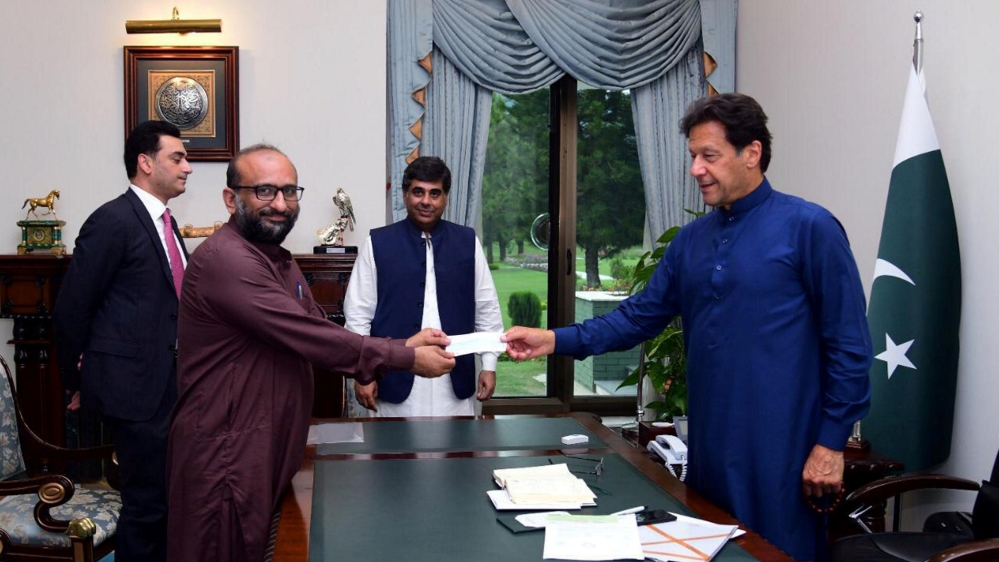 Pakistani Prime Minister Imran Khan receives a cheque from Head of the Edhi Foundation Faisal Edhi, for the Prime Minister's coronavirus disease (COVID-19) relief fund at the Prime Minister House