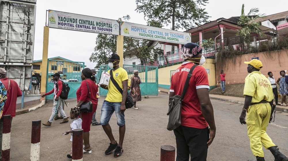 Some people wear masks as they walk by the entrance to the Yaounde General Hospital in Yaounde on March 6, 2020 as Cameroon has confirmed its first case of the COVID-19 coronavirus, a French national