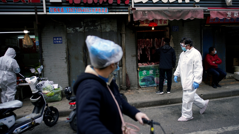 People wearing protective suits is seen at a street market in Wuhan