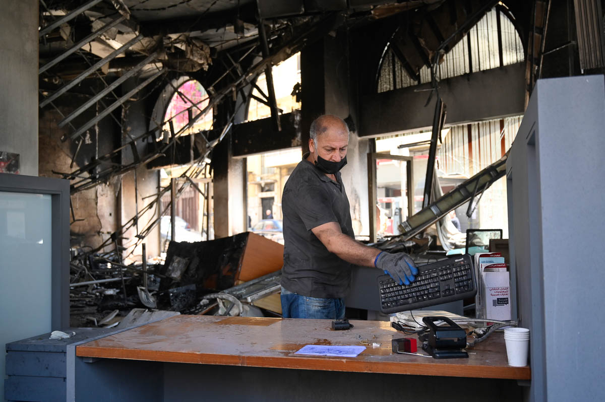epa08389160 A worker cleans inside a bank that was set ablaze by anti-government protesters at Al Nour Square in the northern city of Tripoli, Lebanon, 28 April 2020. At least 30 protesters were injur