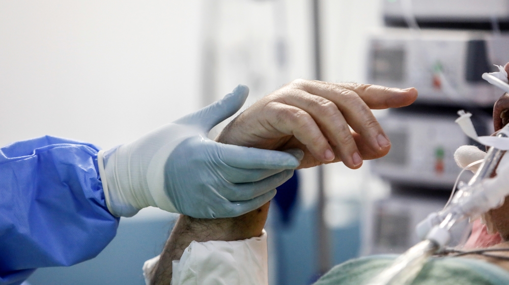 An intubated patient tries to gesture at a medical worker holding his hand at the intensive care unit (ICU) of the Sotiria hospital, following the coronavirus disease (COVID-19) outbreak, in Athens, G