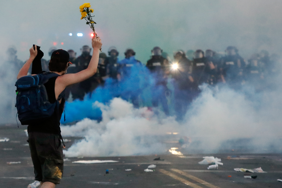 Police move towards a protester after curfew Saturday, May 30, 2020, in Minneapolis. Protests continued following the death of George Floyd, who died after being restrained by Minneapolis police offic