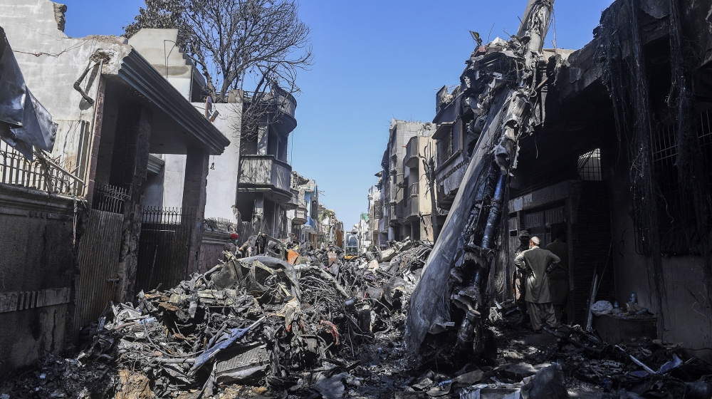 Security personnel stand beside the wreckage of a plane at the site after a Pakistan International Airlines aircraft crashed in a residential area days before, in Karachi on May 24, 2020. Ninety-seven