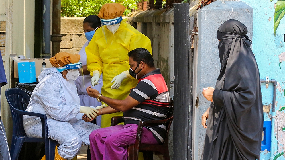 epa08399868 Sri Lankan health workers wearing Personal Protective collecting blood samples from a Muslim man at a locked-down area in Colombo, Sri Lanka, 04 May 2020. The Government has implemented a