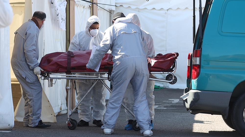 Workers wearing protective equipment transport a body in the grounds of the Central Jamia Mosque Ghamkol Sharif, a temporary morgue set up at a Mosque as the spread of the Coronavirus disease (Covid-1