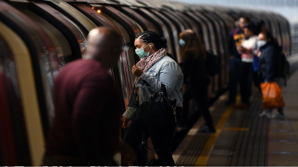 Commuters wearing PPE (personal protective equipment), including a face mask
