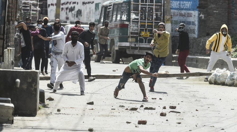 Protesters throw stones at Indian government forces following a gun battle between militants and government forces in Srinagar on May 19, 2020. Two Kashmir militants including a key rebel leader were