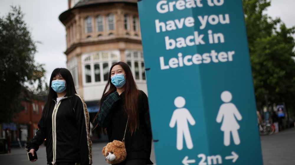 People wearing protective masks walk past a sign, amid the coronavirus disease (COVID-19) outbreak, in Leicester, Britain, June 29, 2020. REUTERS/Carl Recine