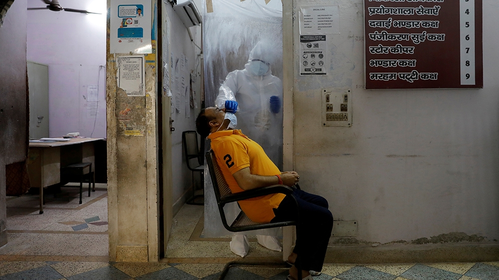 A health worker in personal protective equipment (PPE) collects a sample using a swab from a person at a local health centre to conduct tests for the coronavirus disease (COVID-19), amid the spread of
