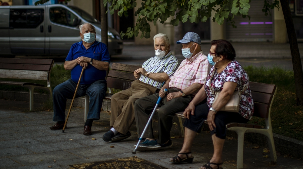 Elder people wearing face masks sit on a bench in a square in Barcelona, Spain, Sunday, May 31, 2020. Spanish Prime Minister Pedro Sánchez says he will ask Spain's Parliament for a final two-week ext