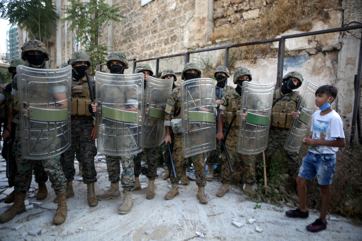 A boy stands next to army soldiers holding position during a demonstration in central Beirut on June 6, 2020. - Protesters poured into the streets of the Lebanese capital to decry the collapse of the