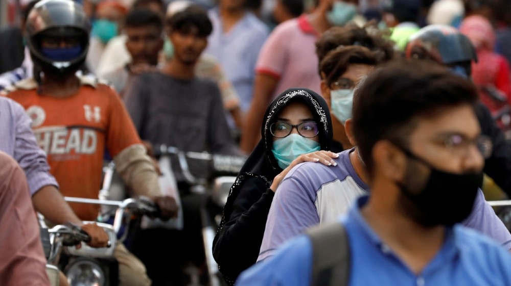 A woman rides on a motor bike as she wears a protective face mask amid the rush of people outside a market as the outbreak of the coronavirus disease (COVID-19) continues,