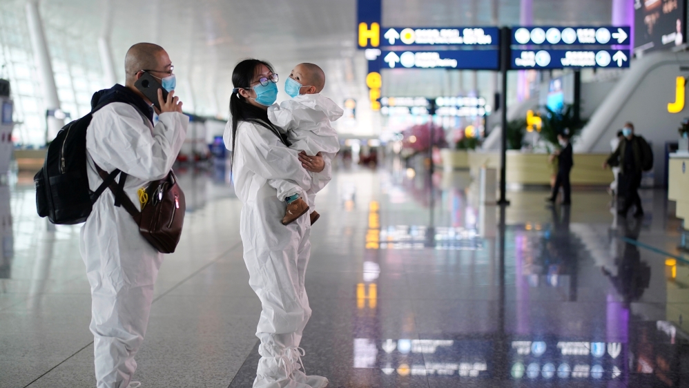 Travellers in protective suits are seen at Wuhan Tianhe International Airport in Wuhan
