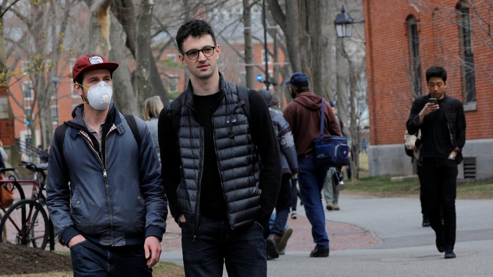 A student wearing a mask walks through the Yard at Harvard University in Cambridge