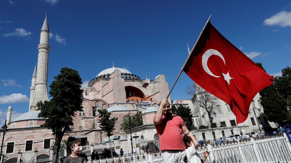 A man waves a Turkish Flag in front of the Hagia Sophia or Ayasofya, after a court decision that paves the way for it to be converted from a museum back into a mosque, in Istanbul