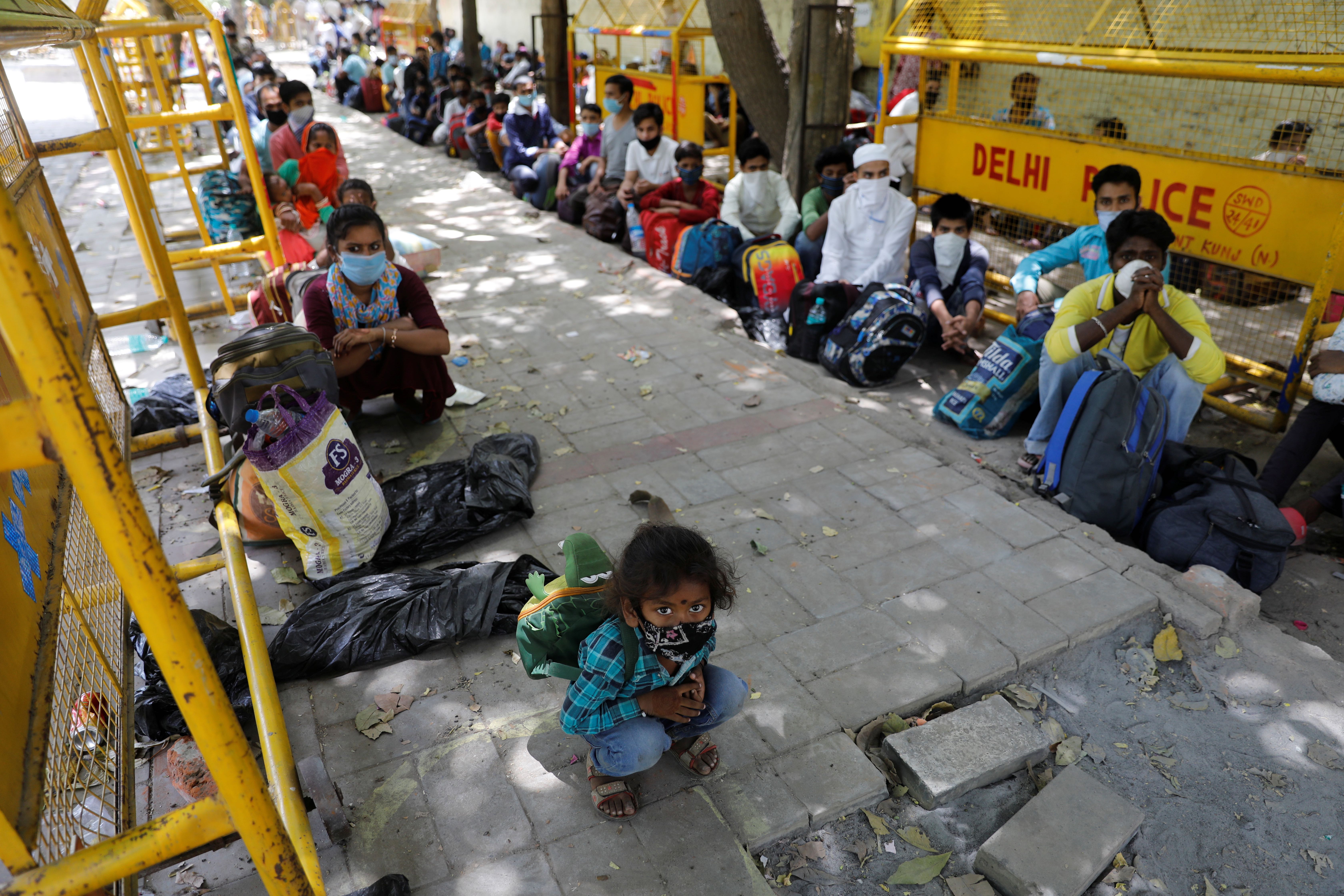 Migrant workers and their families wait to get on a bus to reach a railway station to board a train to their home state of Uttar Pradesh, during an extended lockdown to slow the spreading of the coronavirus disease in Delhi, India
