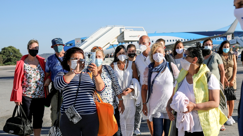 A woman takes a picture of Greek Tourism Minister Harry Theoharis as he welcomes passengers from Germany, who were frontline workers during the coronavirus disease (COVID-19) outbreak, after landing o